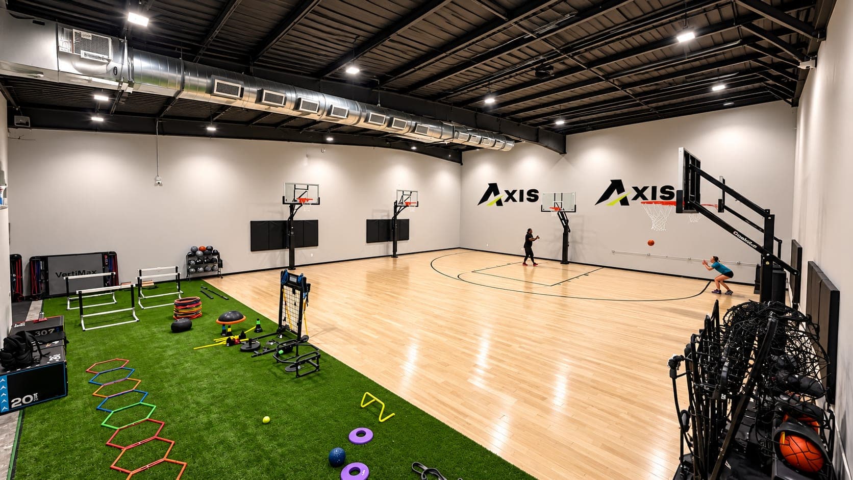 The Axis Sports Lab training floor: a turf lane of agility gear beside the hardwood court